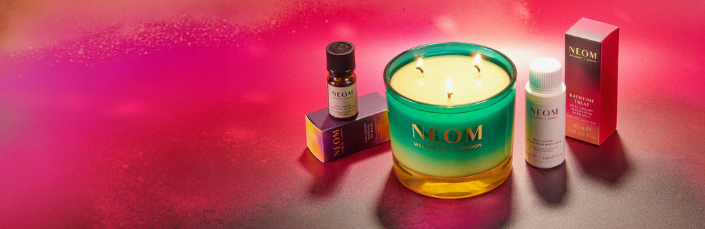 NEOM christmas candle and products on a pink gradient background