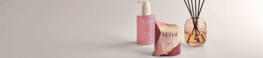 NEOM home & body products including a candle, hand wash, and reed diffuser on a neutral background