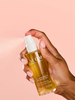 NEOM pro-vitamin D3 dry body oil spray applied from hand for nourishing skin hydration