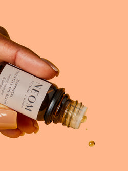 NEOM Happiness essential oil blend dropping from bottle with neroli, mimosa and lemon