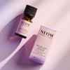 NEOM Bedtime Hero essential oil blend bottle beside its product box on a softly lit background.