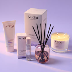 NEOM product range including a candle, diffuser, and other items on a light purple background