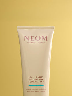 NEOM Real Luxury Magnesium Body Butter tube on a yellow background