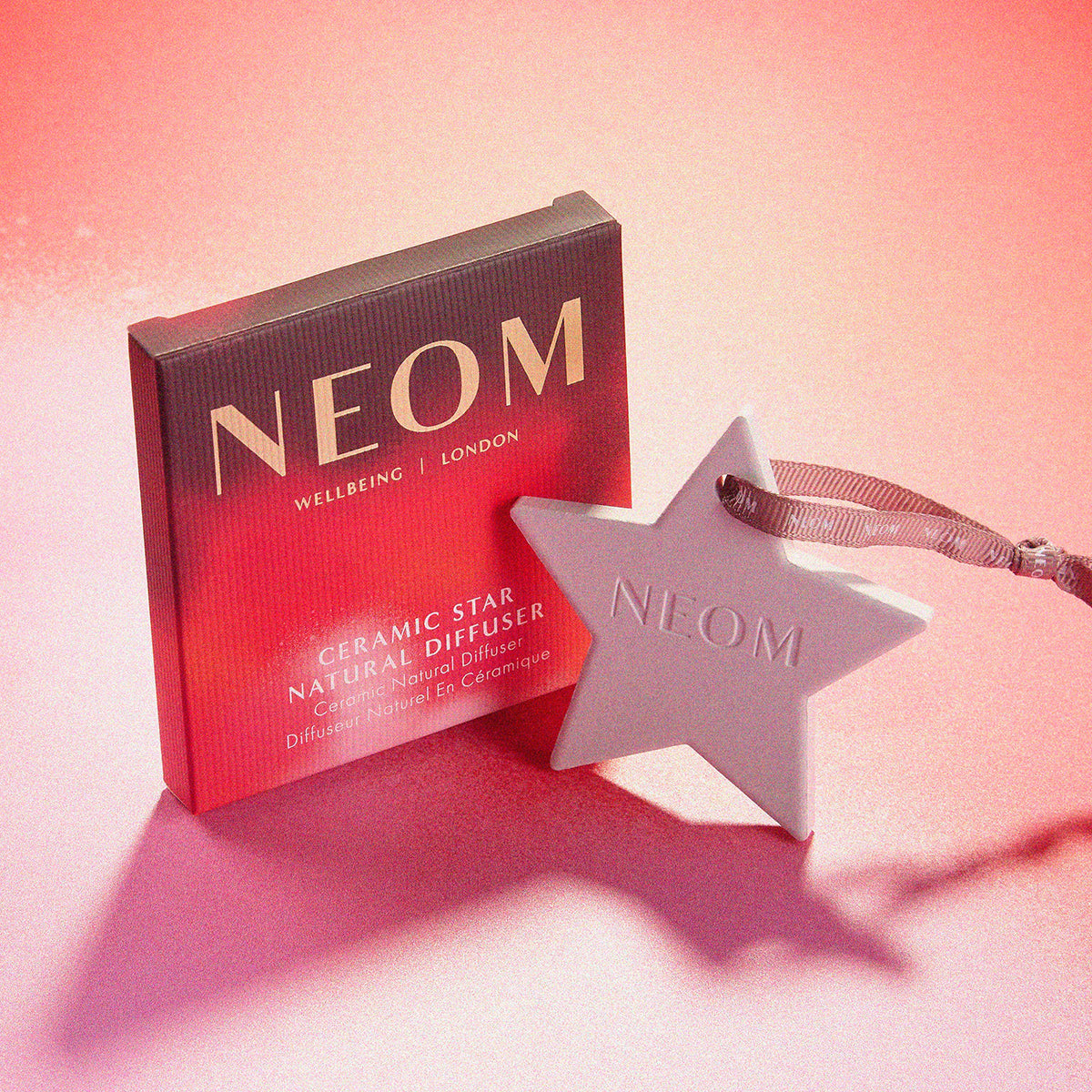 NEOM ceramic star diffuser with packaging on a pink background