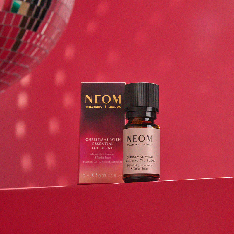 NEOM Christmas Wish Essential Oil Blend bottle and packaging on a red background