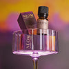 Neom essential oil blend and bottle on a purple stand with a gradient background
