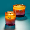 Two NEOM candles with a gradient colour scheme on a blue background