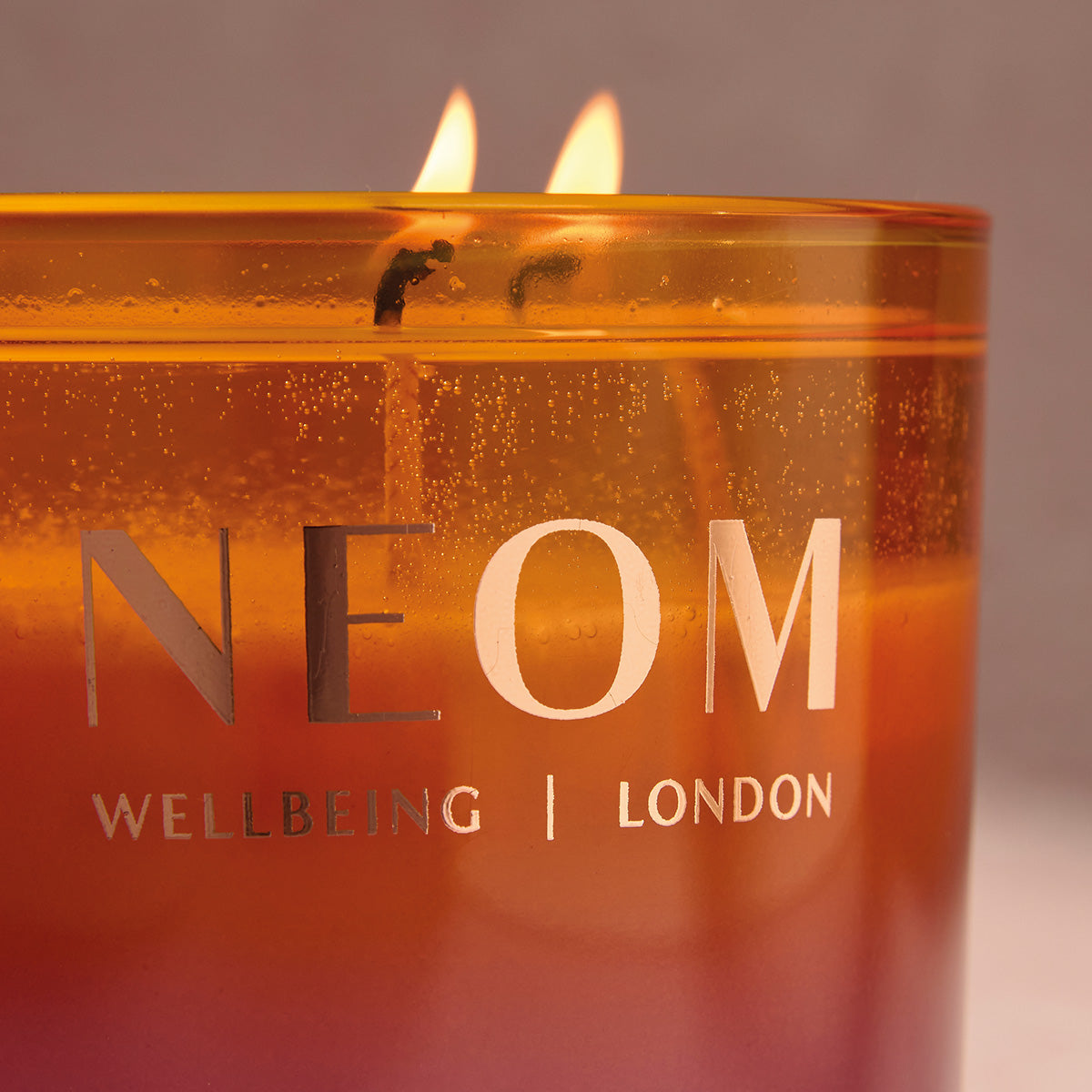 NEOM candle with flames on a neutral background