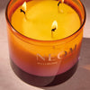 NEOM wellbeing candle with three wicks on a neutral background