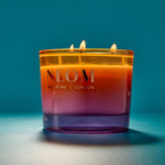 NEOM candle with a gradient colour on a blue background