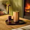 NEOM Pod Mini+ on a wooden table with a fireplace in the background