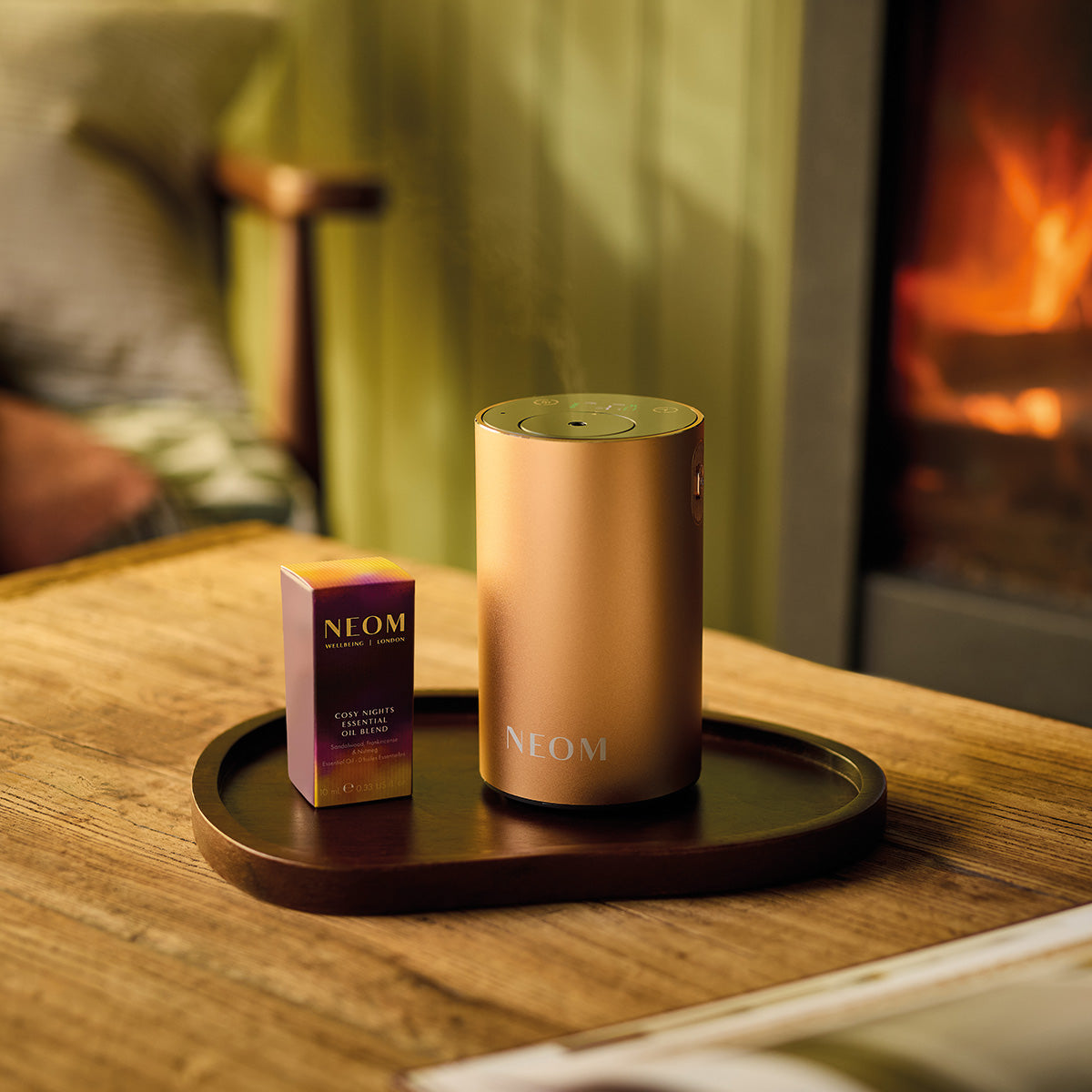 NEOM Pod Mini+ on a wooden table with a fireplace in the background