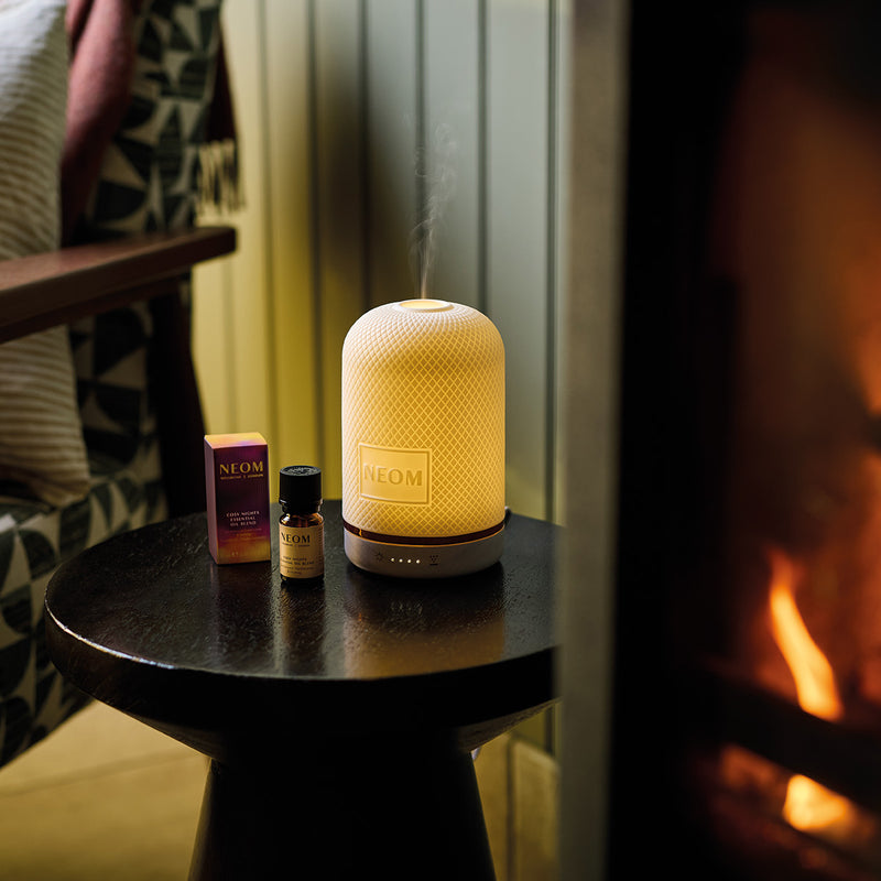 NEOM diffuser on a table with a fireplace in the background