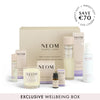NEOM wellbeing box with various items including candles and bottles on a white background.