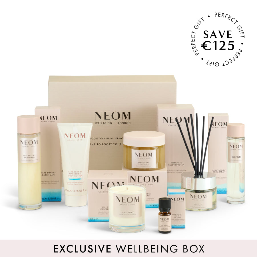 NEOM wellbeing box with various items including candles and bottles on a white background.