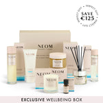 NEOM wellbeing box with various items including candles and bottles on a white background.