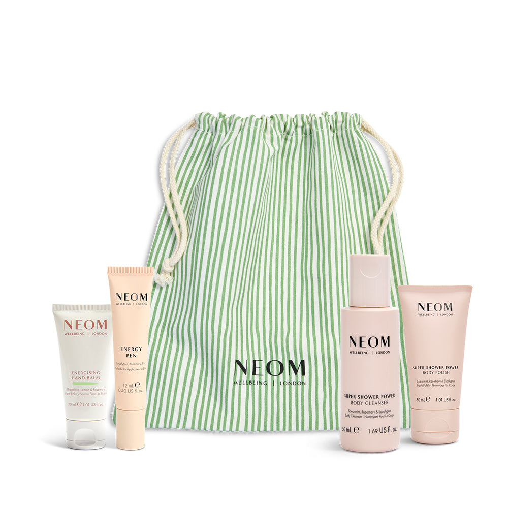 NEOM skincare products with a green striped drawstring bag on a white background