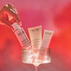 Hand holding NEOM skincare products against a red gradient background