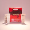 NEOM skincare products including a red box on a light pink background