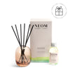 NEOM  diffuser set with rose gold diffuser, black reeds, and small bottle on a white background