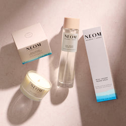 NEOM products including a candle, room spray, and packaging on a neutral background
