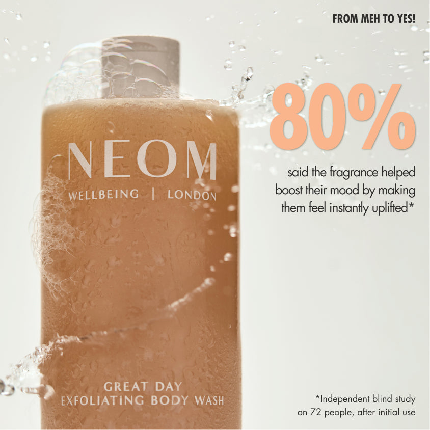 “NEOM Great Day Exfoliating Body Wash bottle with foam beside a sliced citrus fruit. Text reads: ‘Not just a wash, a mood switch! 100% natural fragrances.’ Additional text: ‘Wild mint known to be cooling, invigorating and refreshing. Mandarin to help uplift and boost mood. Olive stone, volcanic perlite and aloe vera gently smooth and soften skin.’”