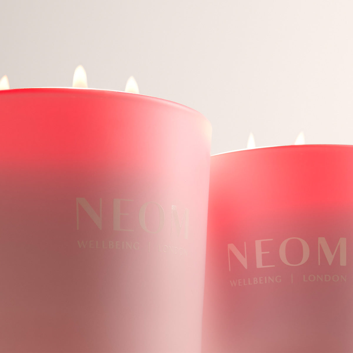 Two NEOM candles with a gradient effect on a light background