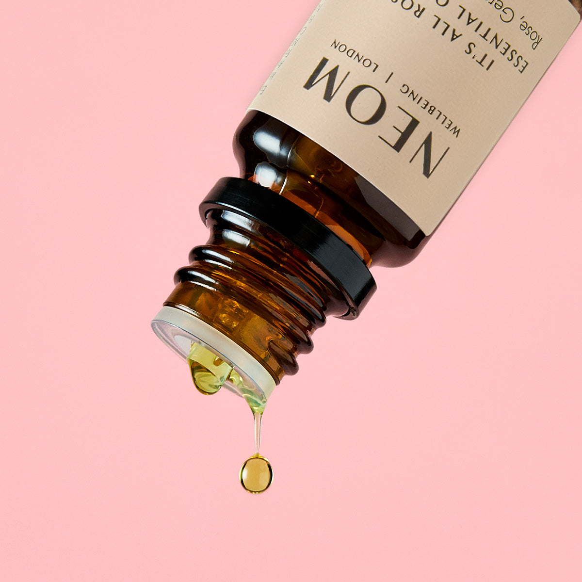 NEOM essential oil dropper with a beige label on a pink background