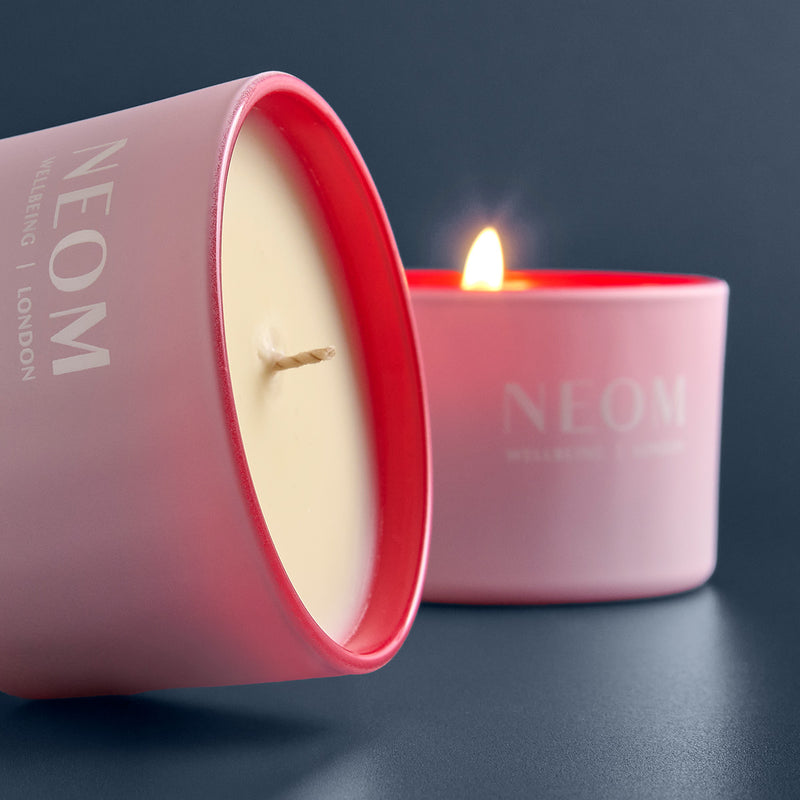 NEOM candle in a pink container on a dark background
