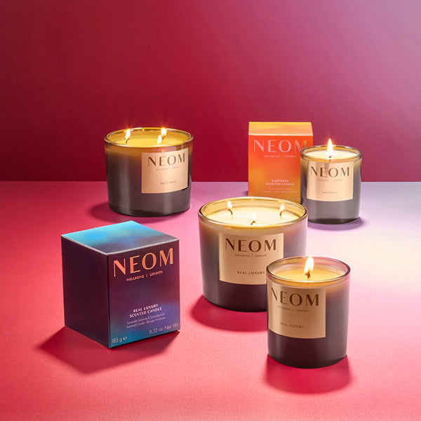 NEOM limited edition real luxury and happiness candles on a pink gradient background