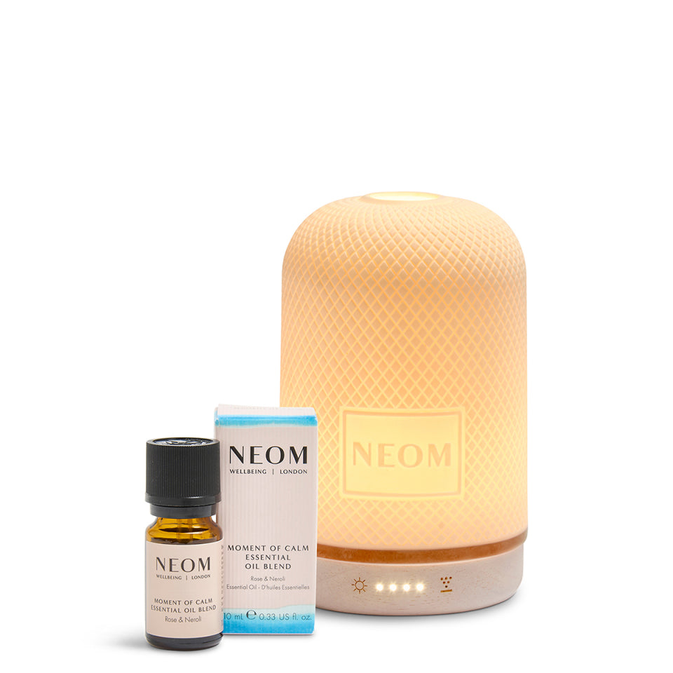 NEOM pod diffuser, essential oil bottle, and box on a white background