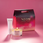 NEOM products including a candle, body milk, and packaging on a pink background