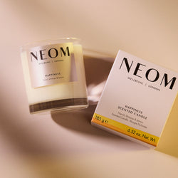 NEOM Happiness scented candle and packaging on a beige background