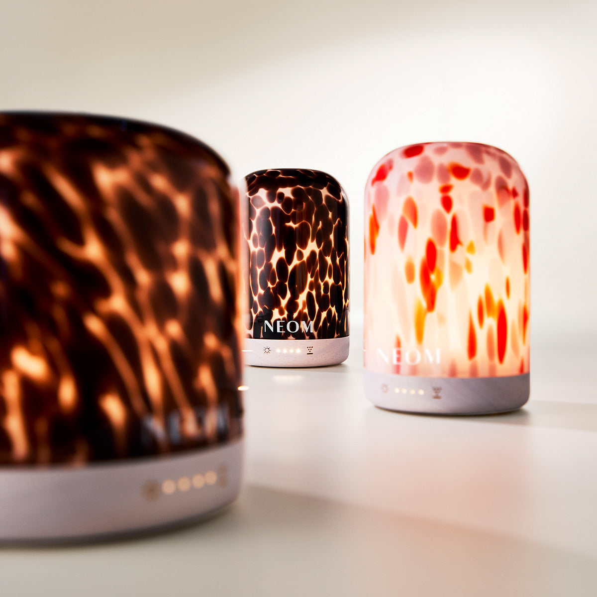 Three NEOM diffusers with tortoiseshell, leopard print diffuser on a light background.
