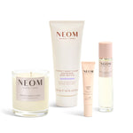 NEOM products including a candle, body butter, sleep pen, and pillow mist on a white background
