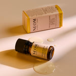 NEOM Orange Blossom & Neroli essential oil blend bottle lying beside its box with small pools of oil on the surface.