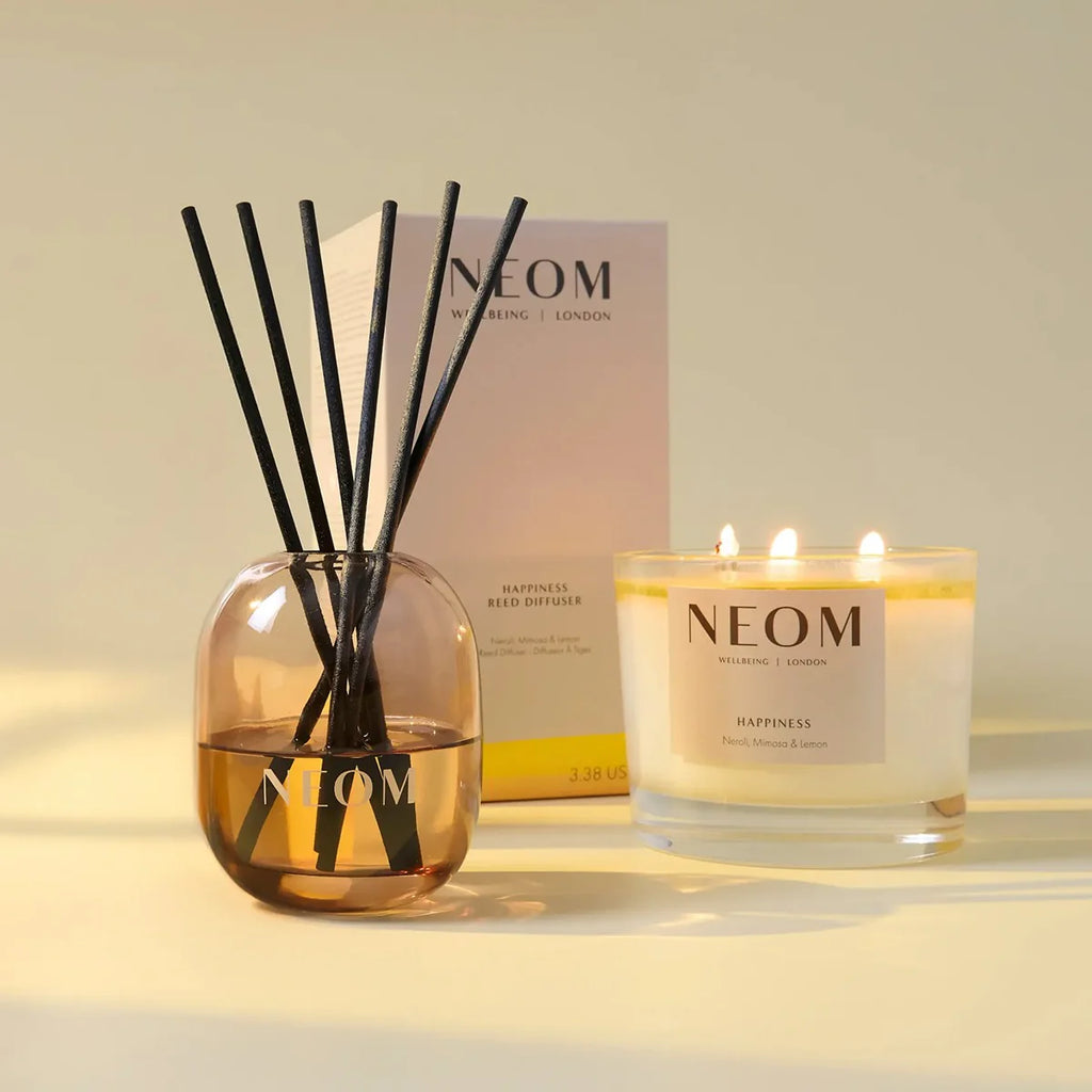 NEOM Happiness reed diffuser and three-wick scented candle home fragrance set with neroli, mimosa and lemon.