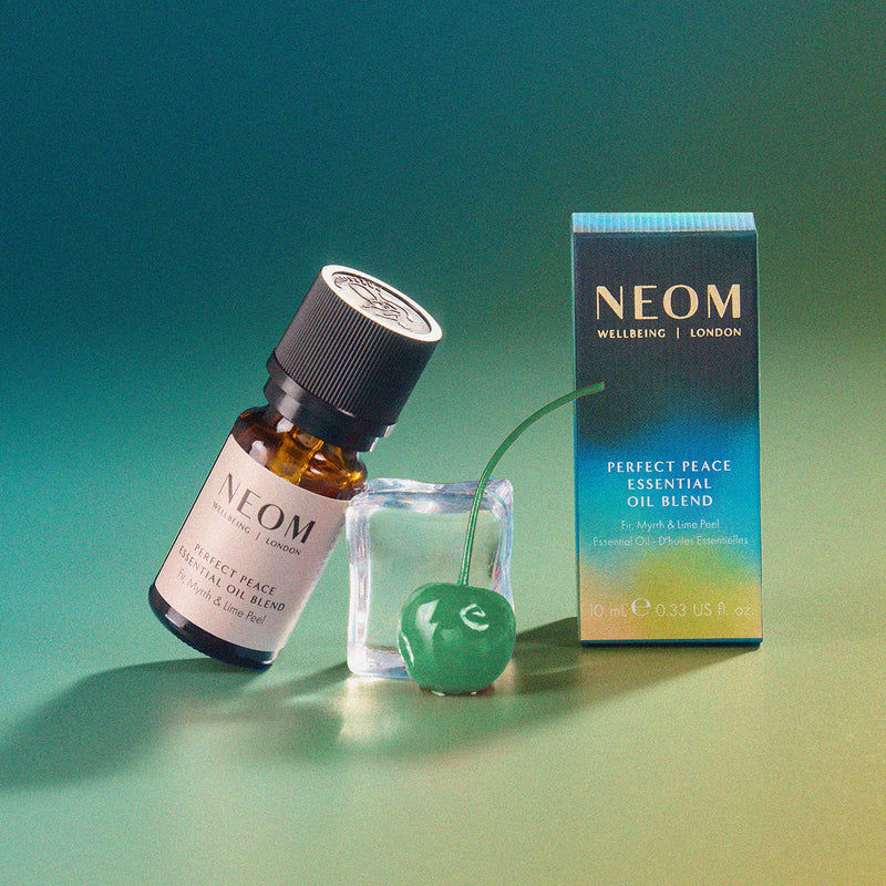 NEOM Perfect Peace Essential Oil Blend with packaging on a gradient background