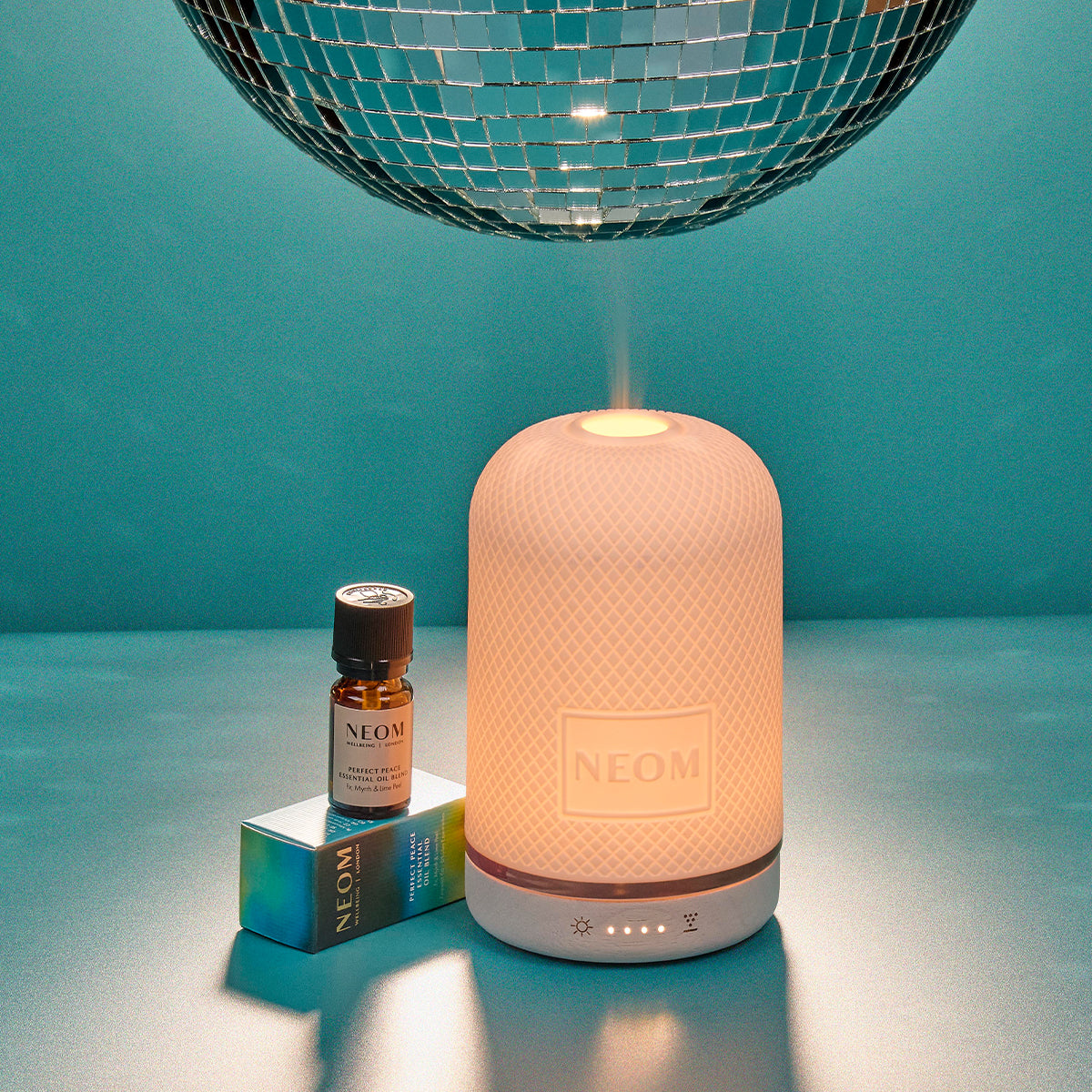 Neom diffuser with bottle and packaging on a teal background