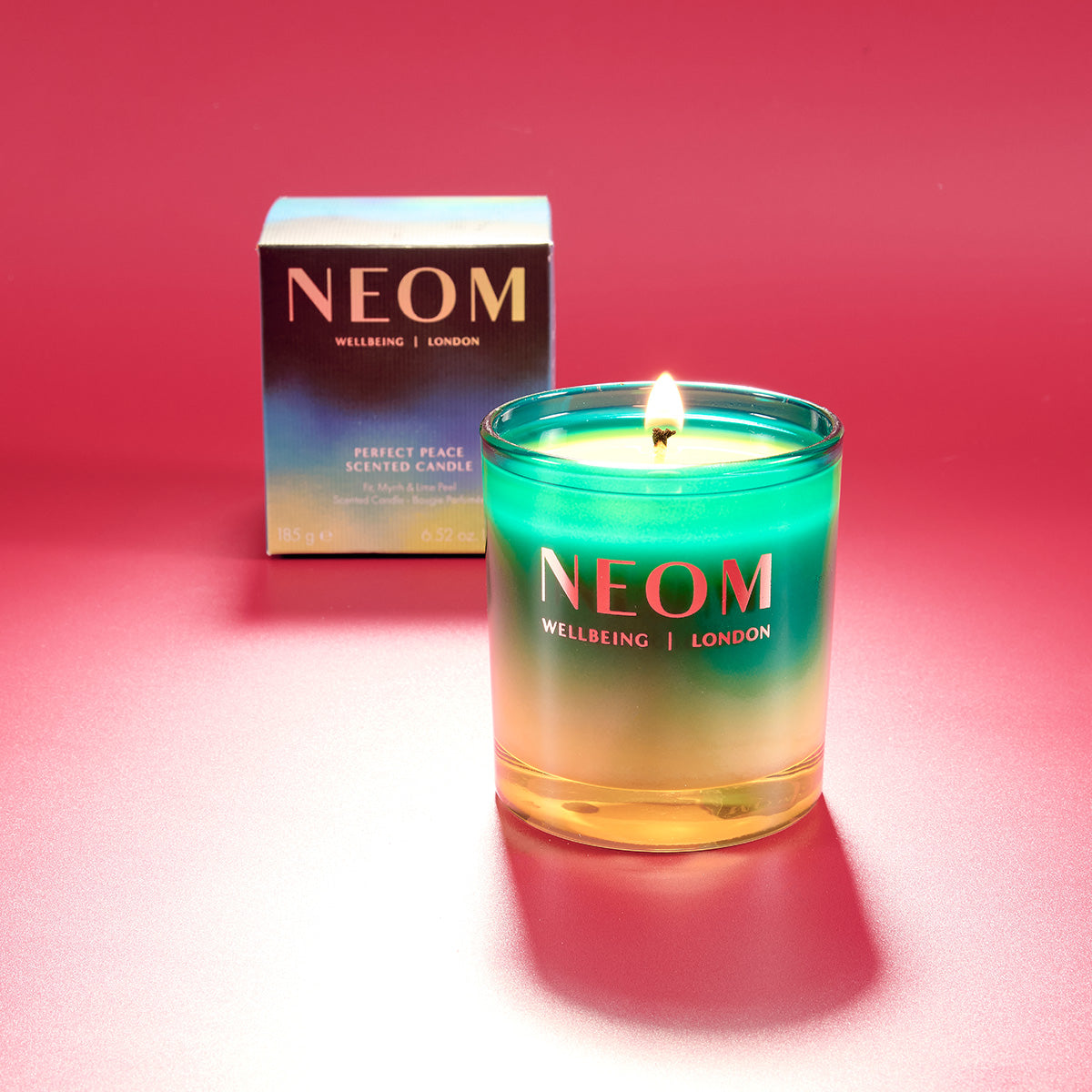 NEOM candle with a gradient effect on a red background