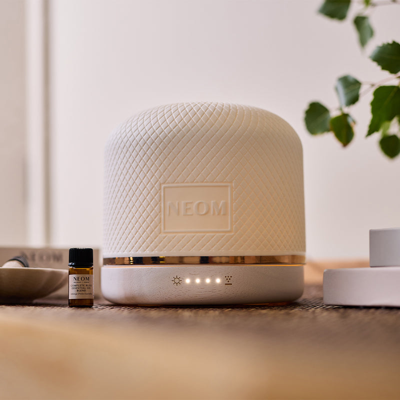 NEOM Wellbeing Pod Luxe aromatherapy diffuser styled with essential oils and home décor.