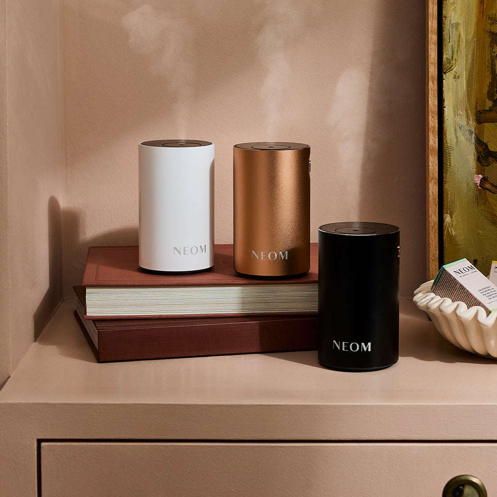 NEOM Wellbeing Pod Mini+ in White, Rose Gold and Black on a table side