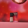 NEOM essential oil bottle and packaging on a pink surface with a disco ball in the background