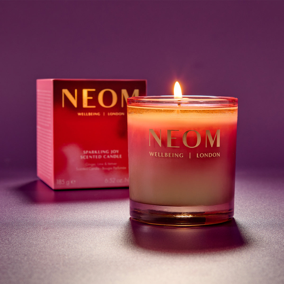 NEOM candle and packaging on a purple background