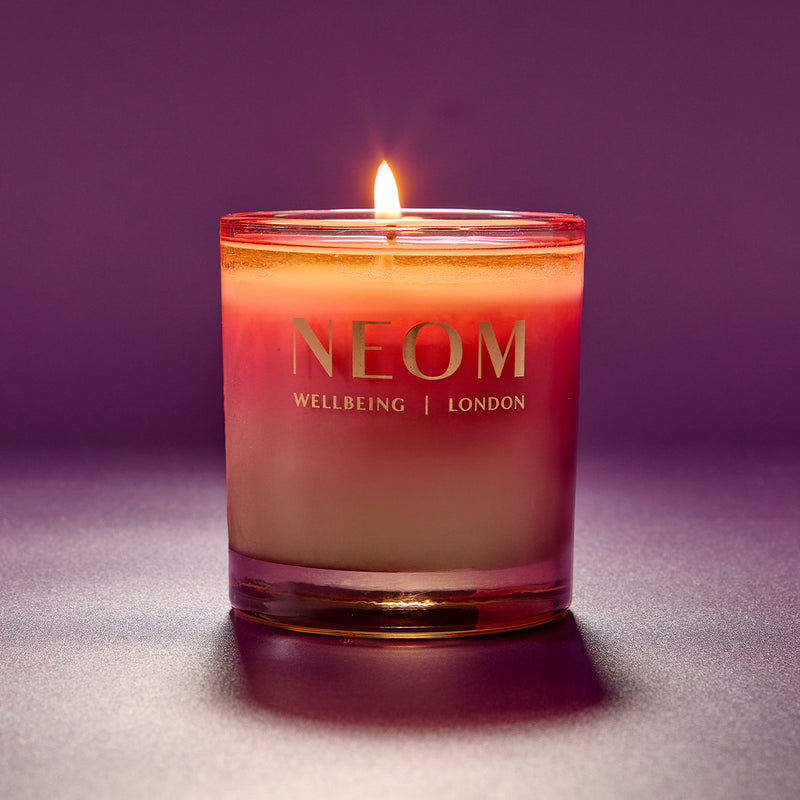 NEOM candle with a purple gradient on a matching background