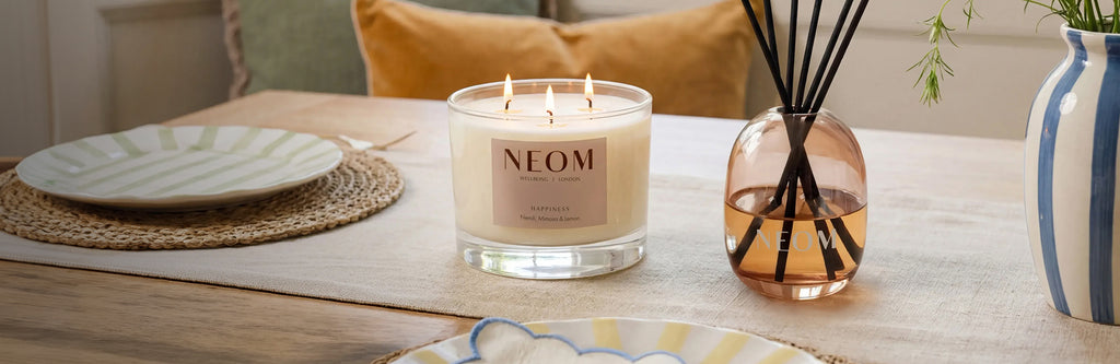 NEOM Happiness scented candle and reed diffuser styled on dining table.