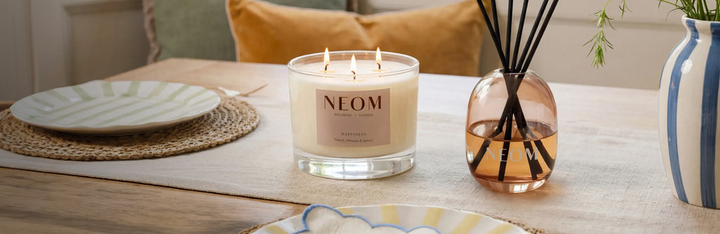 NEOM Happiness scented candle and reed diffuser styled on dining table.