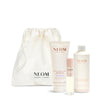 NEOM skincare products including a drawstring bag, body butter, and other items on a white background