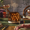 Tortoiseshell print pod diffuser on a table with drinks and a stone wall background