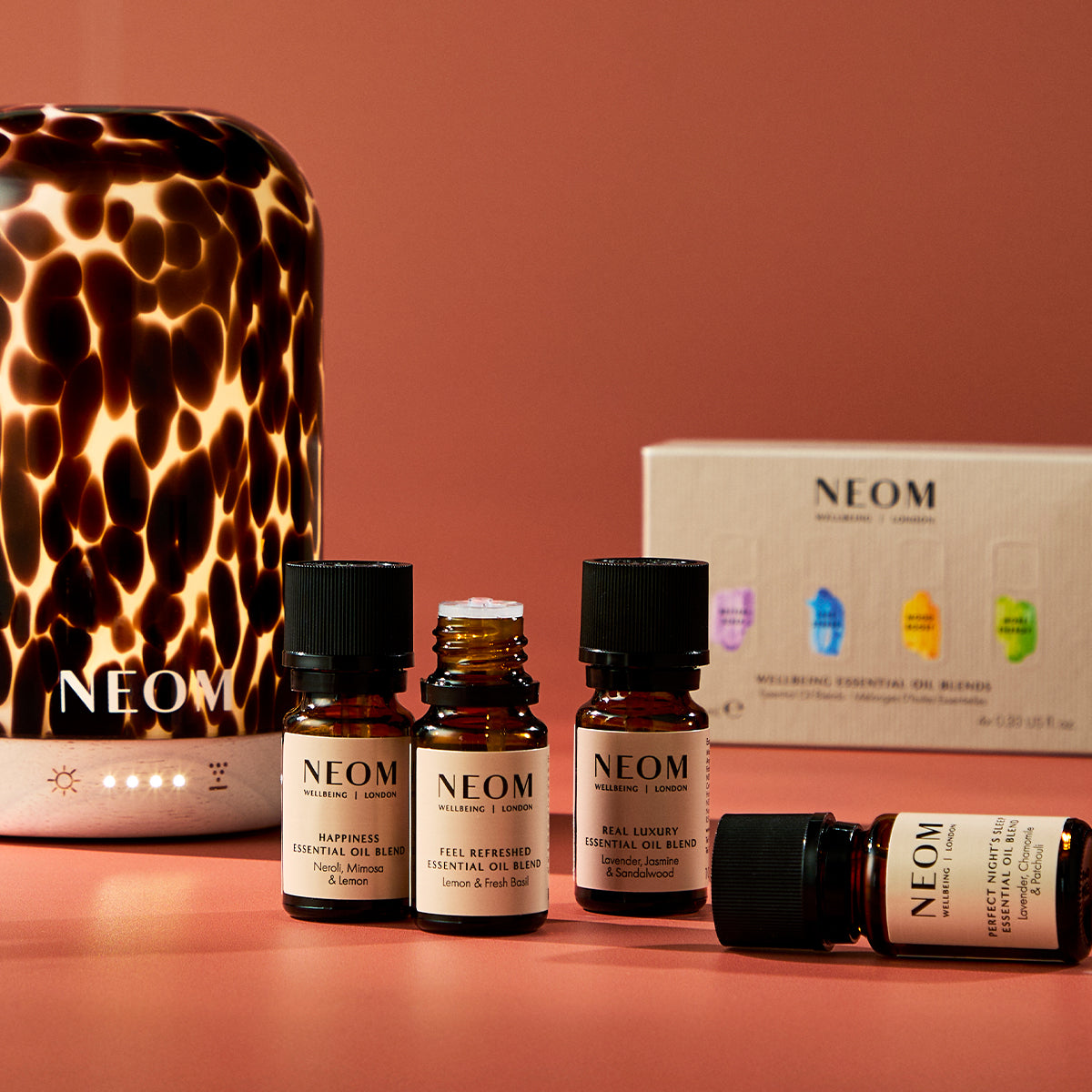 NEOM essential oil and diffuser on a pink background